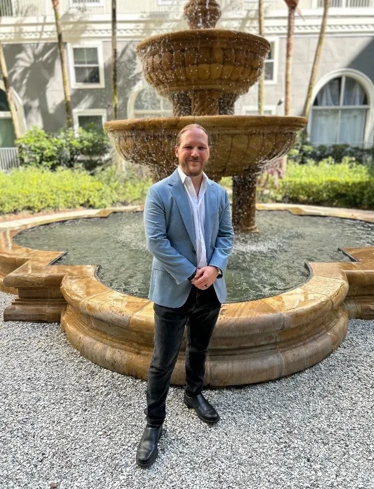 Dr. Karan Narwal standing outdoors in front of a stone water fountain