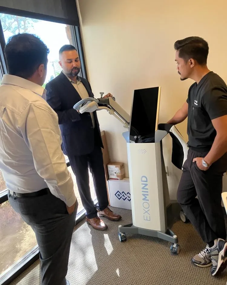 Clinical staff demonstrating the setup of a medical machine with screen