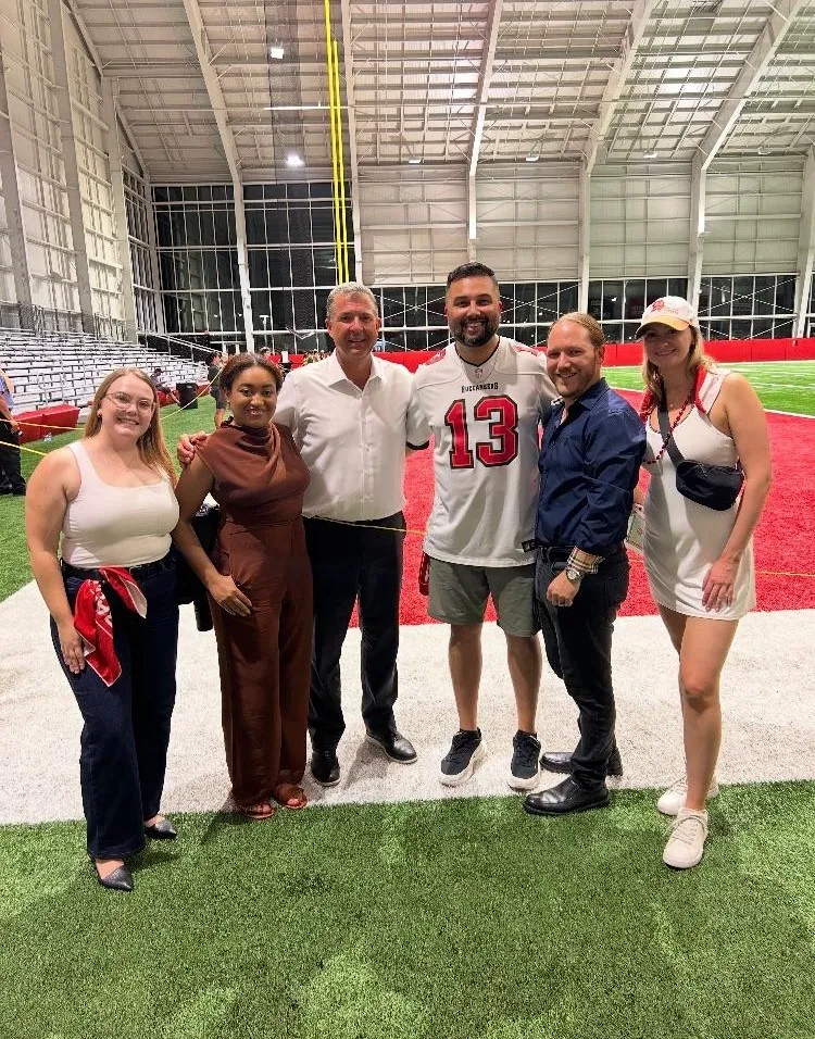 Team members gathered on an indoor athletic turf field