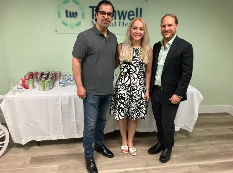 Dr. Karan Narwal and partners posing in front of the Turnwell Mental Health banner